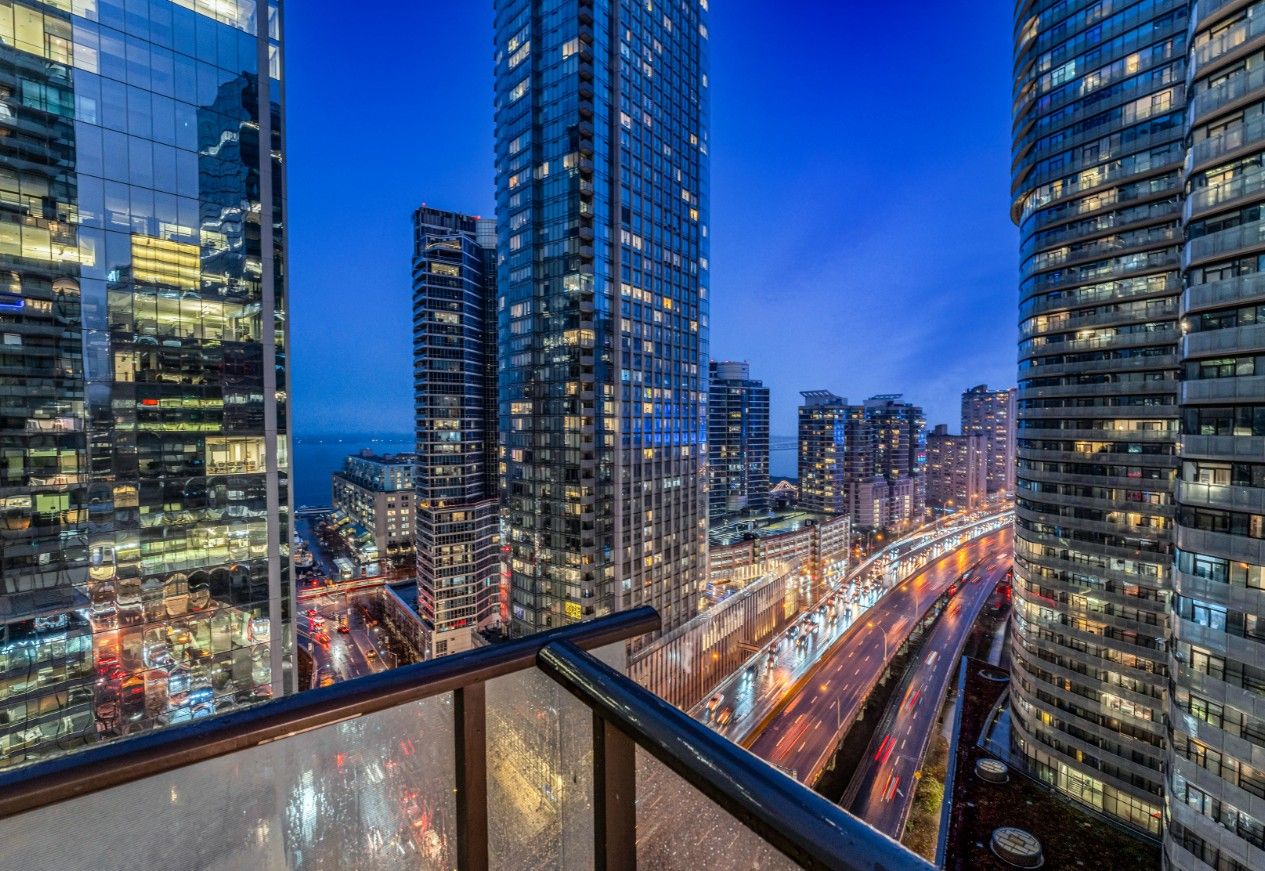 A cityscape at dusk with high-rise buildings and a busy road.