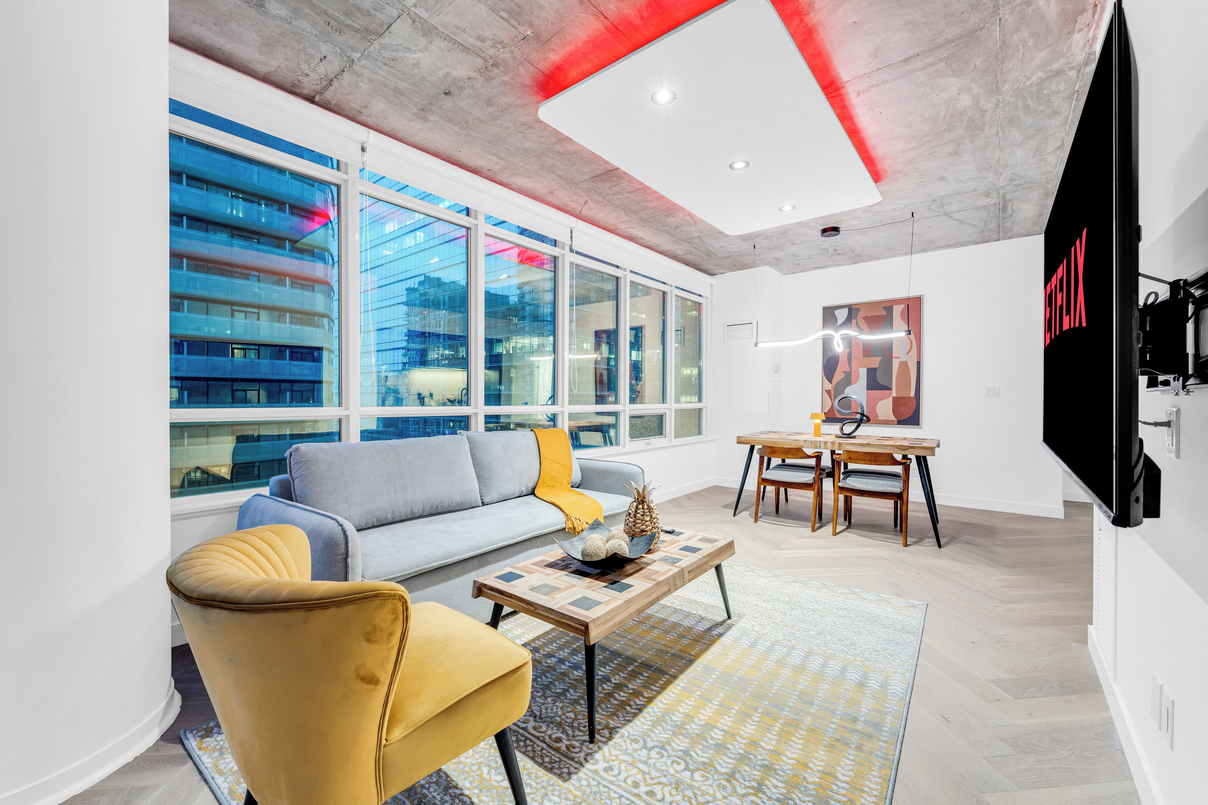Un salon moderne comprenant un canapé, un fauteuil, une table basse et un coin repas avec des chaises et une table.