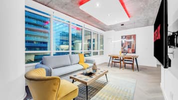 Un salon moderne comprenant un canapé, un fauteuil, une table basse et un coin repas avec des chaises et une table.