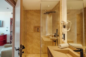 A modern bathroom with a glass shower enclosure, a built-in sink, and a hairdryer mounted on the wall. - Art Hotel (Marrakech)