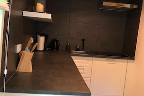A modern kitchen with dark countertops, white cabinets, and a stainless steel range hood. - Charming Apartment with Mountain Views in Nordenau for 6 (Nordenau)