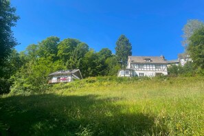 A traditional building with a sloped roof, surrounded by lush greenery and trees. - Cozy Apartment with Mountain Views in Nordenau for 4 (Nordenau)