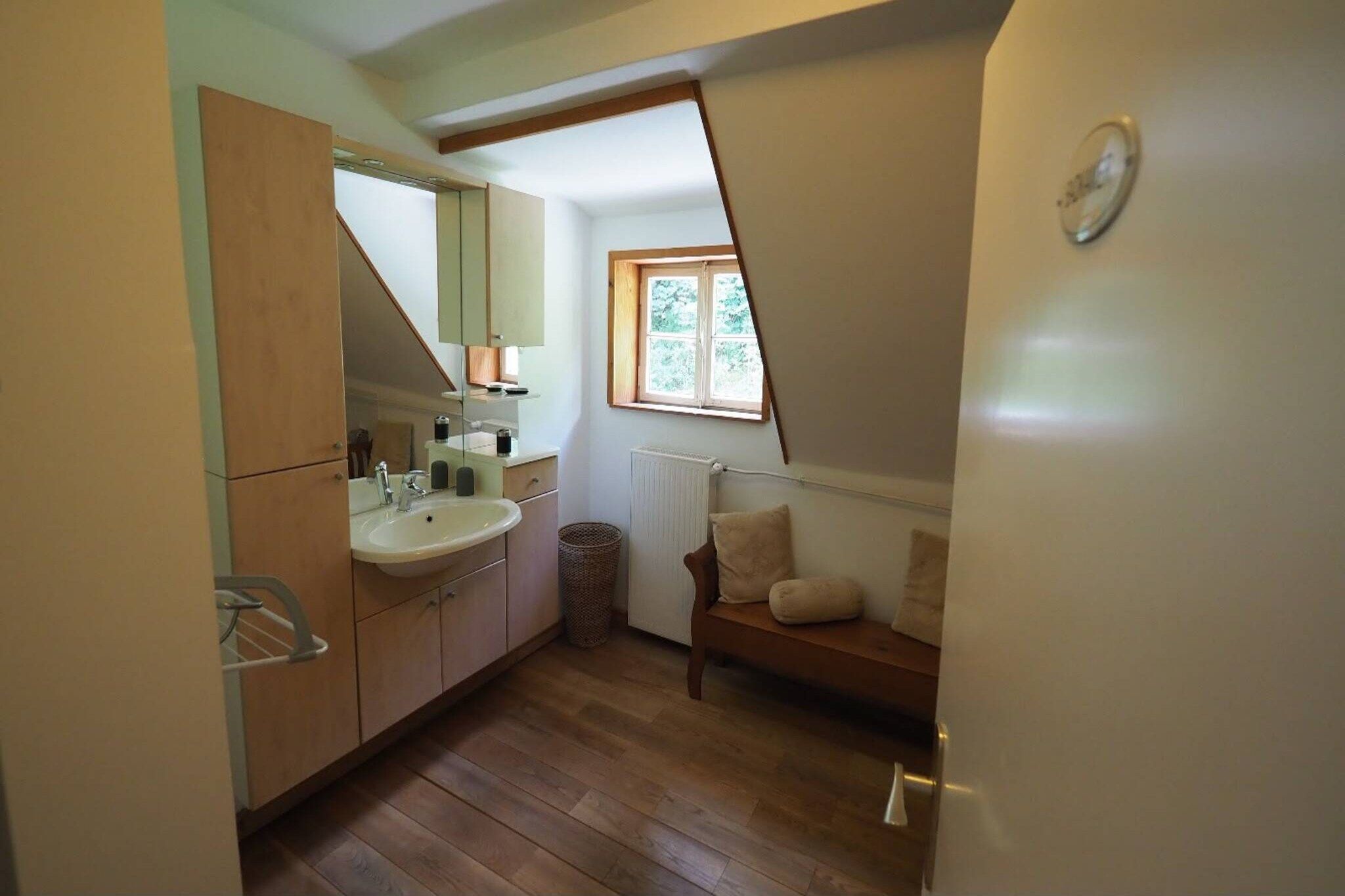 A small bathroom with a sink, mirror, and a window.