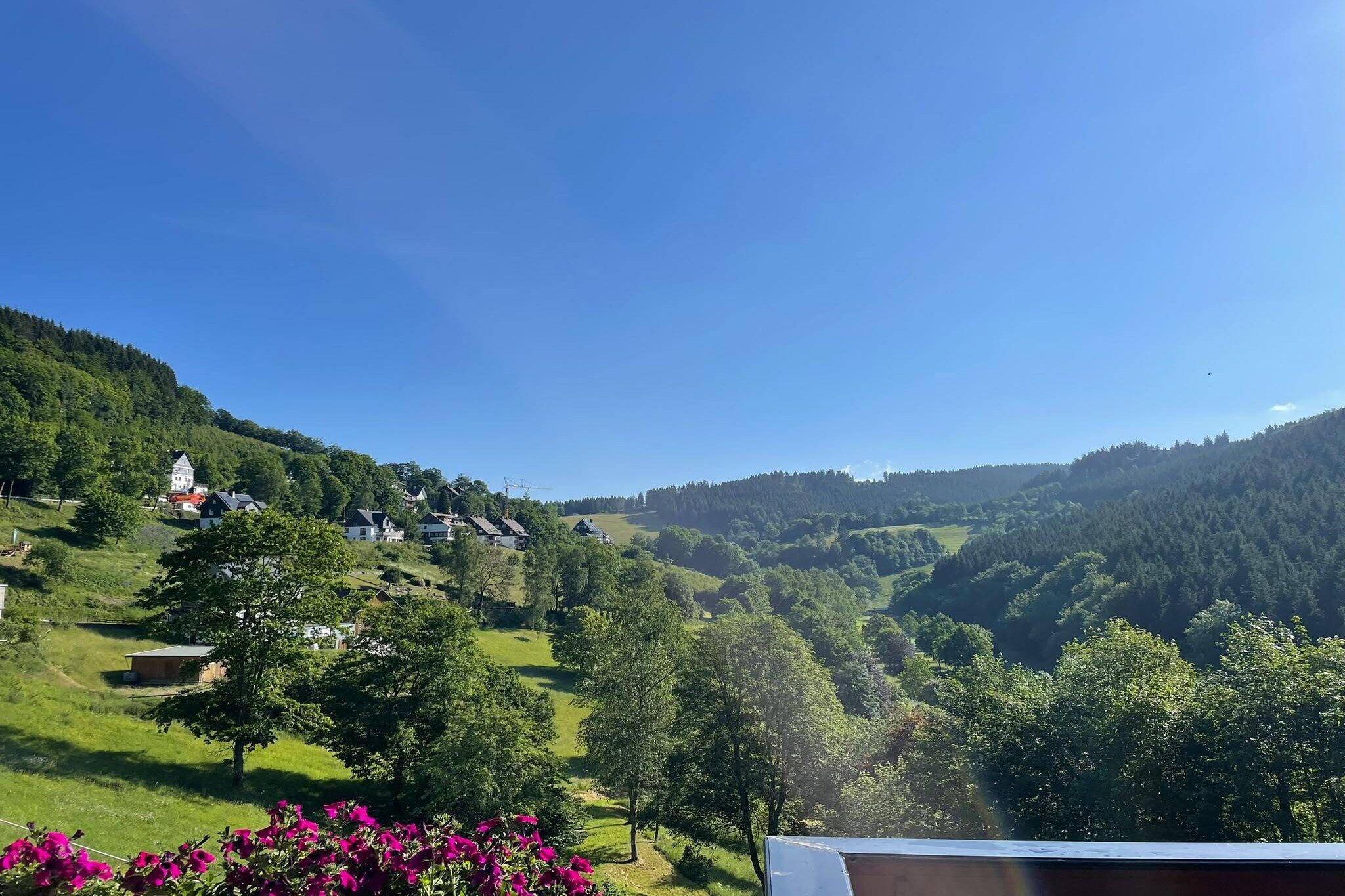 A rural landscape with houses on a hillside, a clear sky, and a view of the valley below.