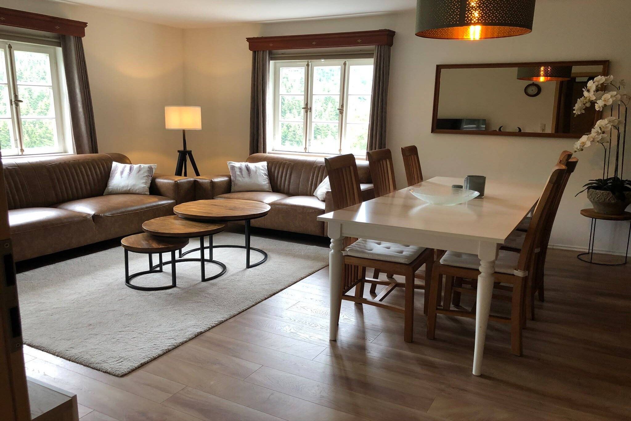 A modern living room with a sofa, round coffee table, dining table, chairs, and a lamp.