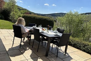 Ein Patio-Garnitur für zwei Personen mit Stühlen, einer Weinflasche und einer Obstschale.