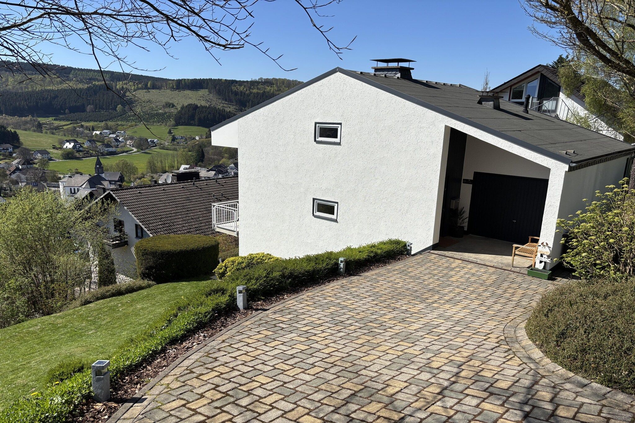 Een modern huis met een geplaveid oprit die naar een garage leidt.