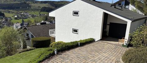 Een modern huis met een geplaveid oprit die naar een garage leidt.