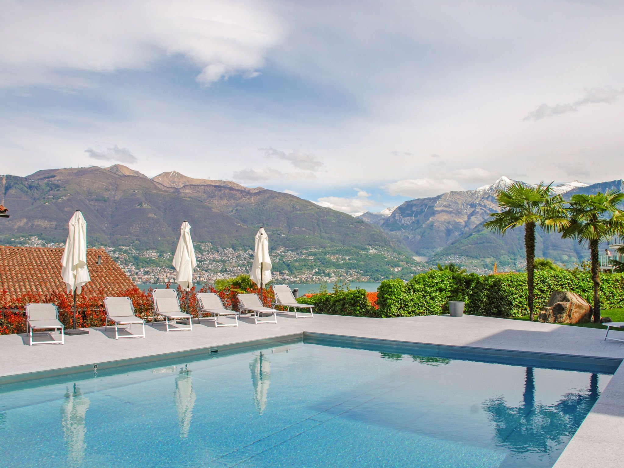 A pool with lounge chairs and umbrellas, overlooking a mountainous landscape.