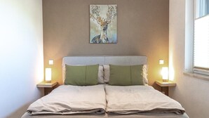 Un letto con testiera, due comodini con lampade e un quadro appeso al muro.