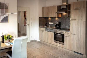 Una cocina moderna con armarios de madera, horno empotrado y cafetera.