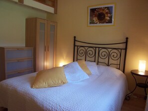 A bed with a metal headboard, a bedside table with a lamp, and a wardrobe. - Gîte Soleil with pool, adults only (18+) (Beaumont-en-Diois)