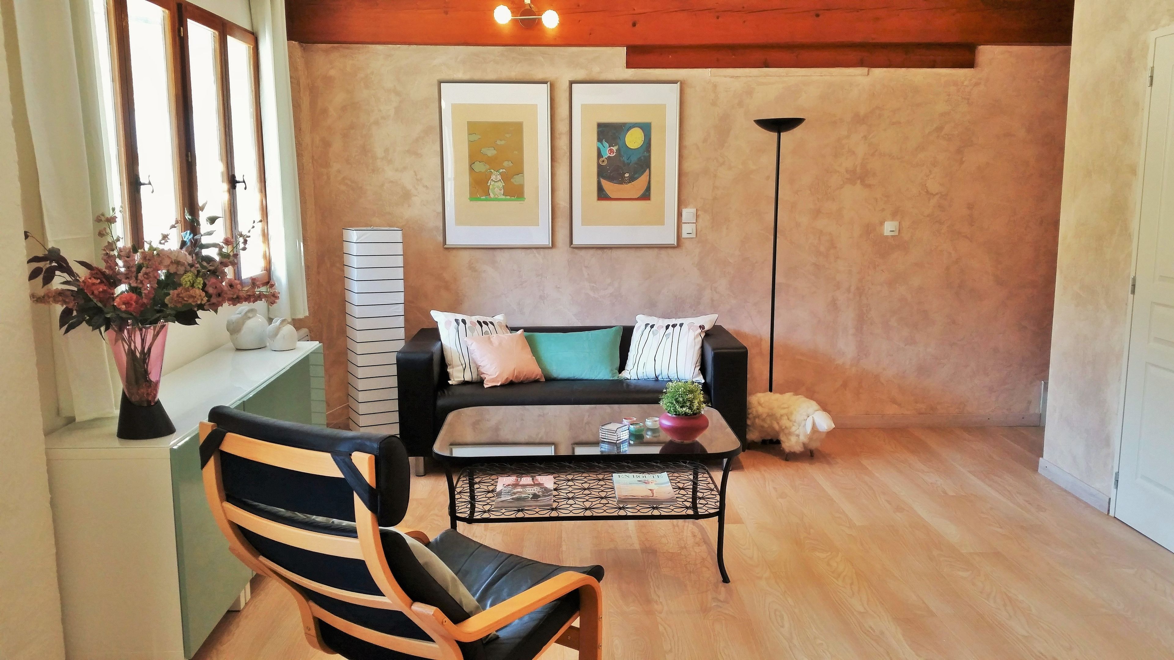 A living room with a sofa, a chair, a coffee table, and two framed artworks on the wall.