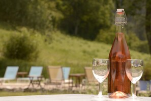 Eine Flasche und zwei Gläser auf einem Tisch mit unscharfem Hintergrund im Freien.