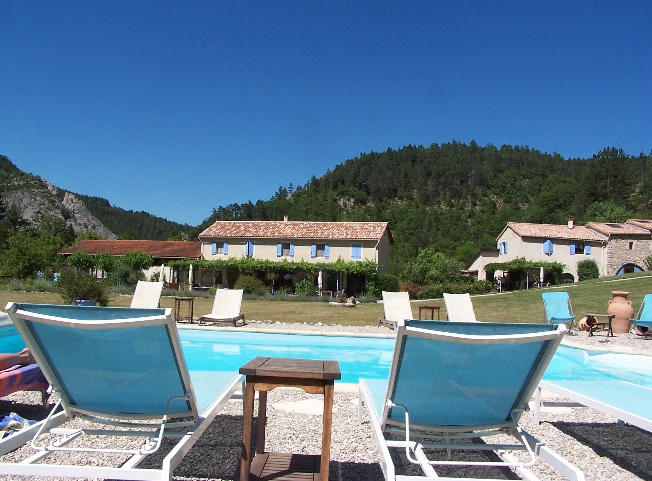 Zona de piscina amb gandules i un edifici amb teulada enrajolada.