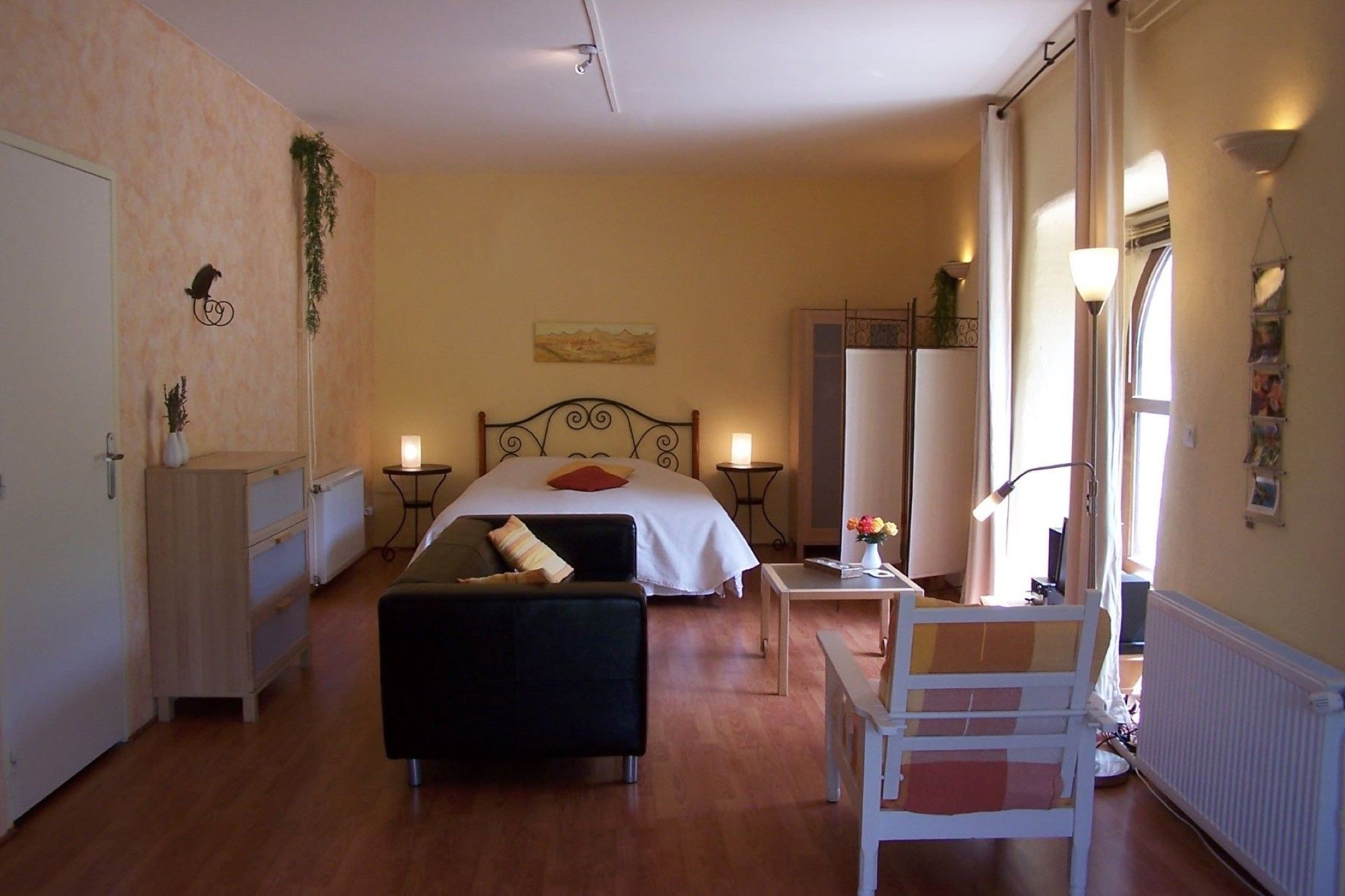 A hotel room with a bed, bedside tables, a chair, a radiator, and a window.