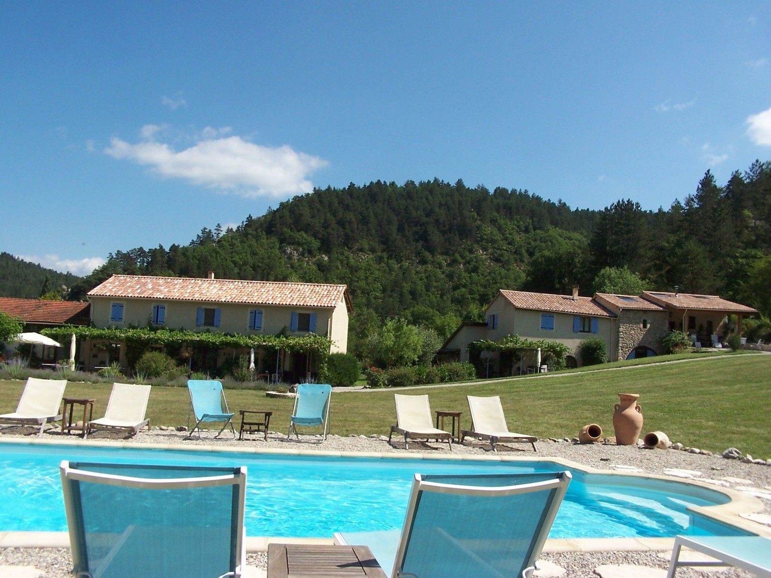 A pool area with lounge chairs and a view of a hillside with buildings.
