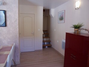 Ein Flur mit Holzboden, einer weißen Tür, einer Treppe, einem roten Schrank und einem gerahmten Bild an der Wand.