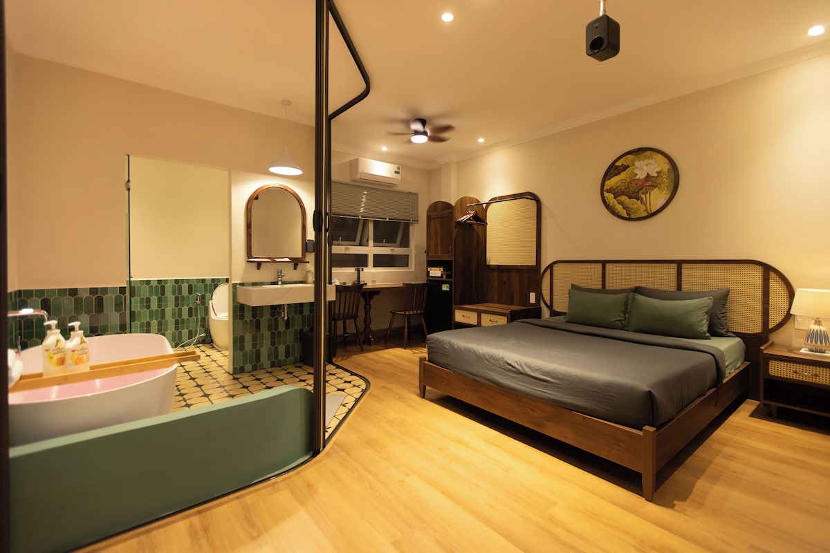 Quarto de hotel com cama, banheiro, escrivaninha e espelho.