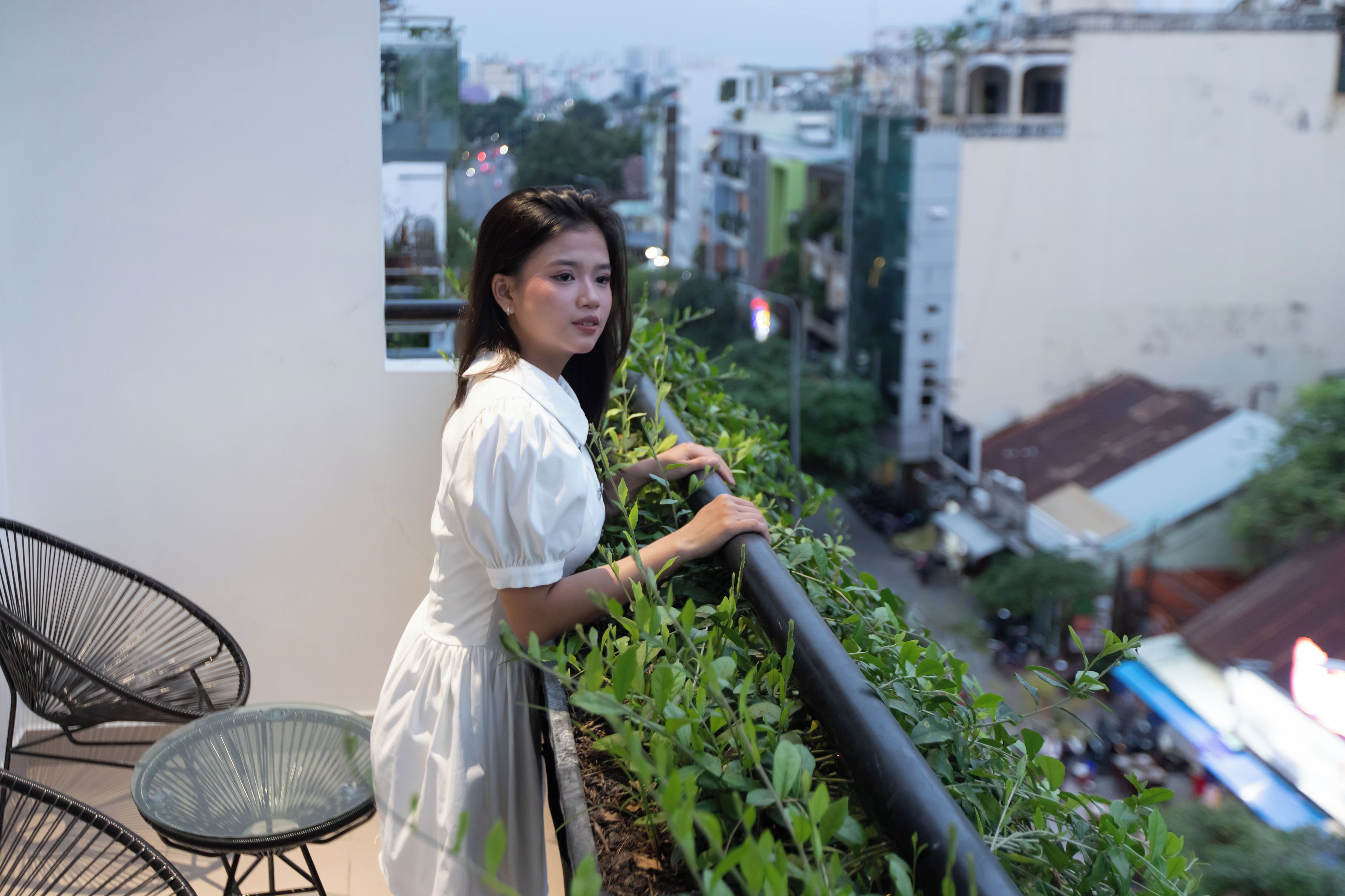 A person standing on a balcony with a view of a cityscape.