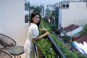 Une personne se tient sur un balcon, d’où l’on peut admirer la vue sur la ville.