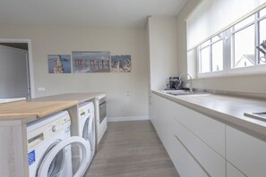 Eine kompakte Küche mit Waschmaschine, Spüle und Fenster mit Blick.