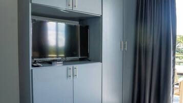 A room with a grey wardrobe, a flat-screen TV, and a patterned rug.