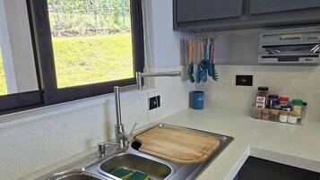 Uma cozinha com janela, pia, tábua de corte de madeira e armários.