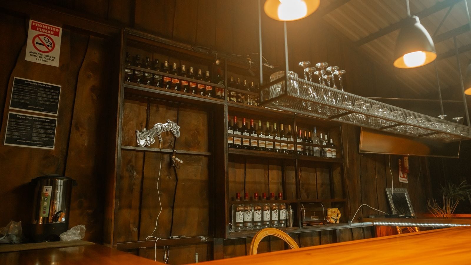 A bar area with shelves of bottles, a coffee machine, and a neon sign.