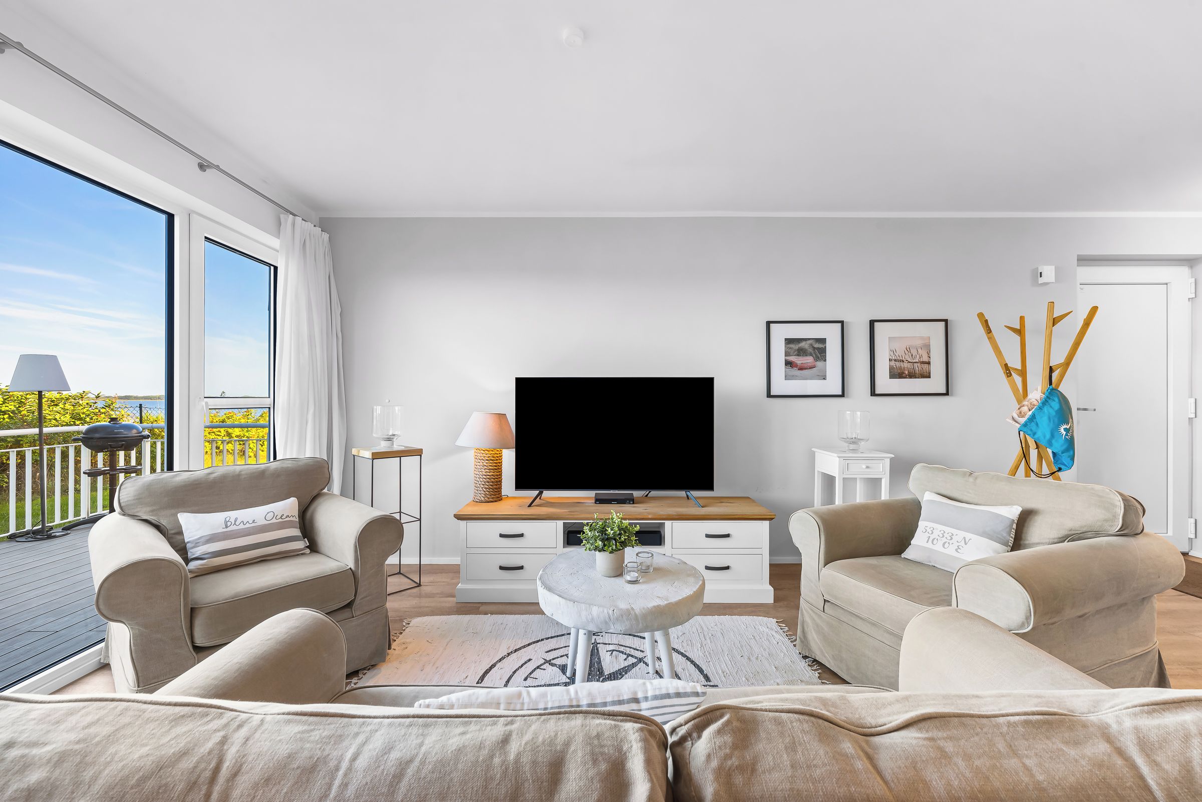 Een moderne woonkamer met een flatscreen televisie, twee banken, een salontafel en een groot raam met uitzicht op het omliggende landschap.