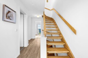 A staircase with wooden steps and a handrail, leading to an upper floor. - SchleiZeit: Vacation Home in the Olpenitz Baltic Sea Resort with Sauna, Hot Tub, and Ocean View (Olpenitz)