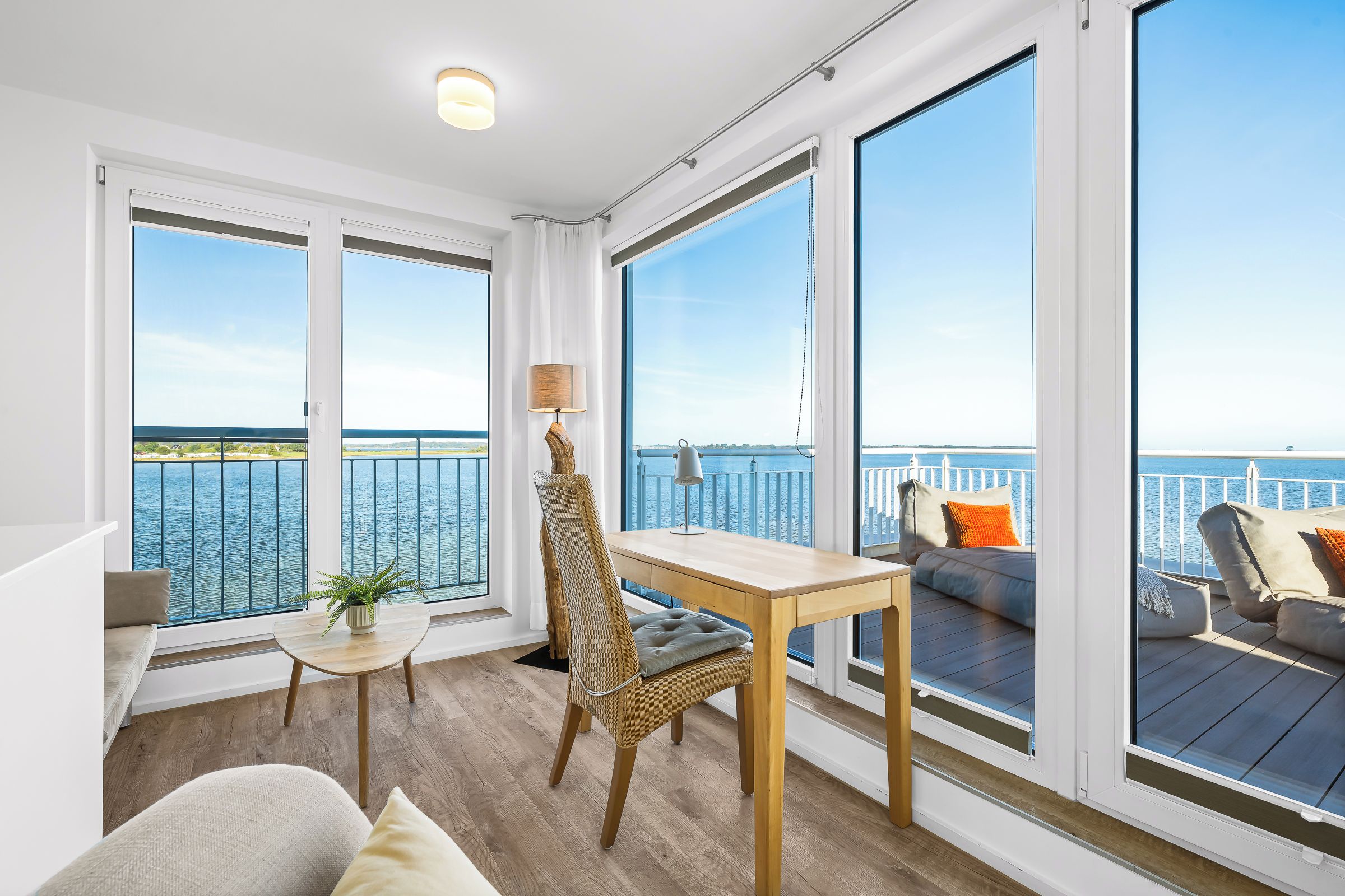 Un intérieur moderne avec un balcon donnant sur une étendue d’eau.