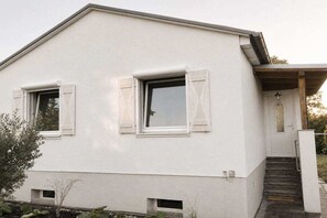 Ein zweistöckiges Gebäude mit flachem Dach, weißen Außenwänden und zwei Fensterläden.
