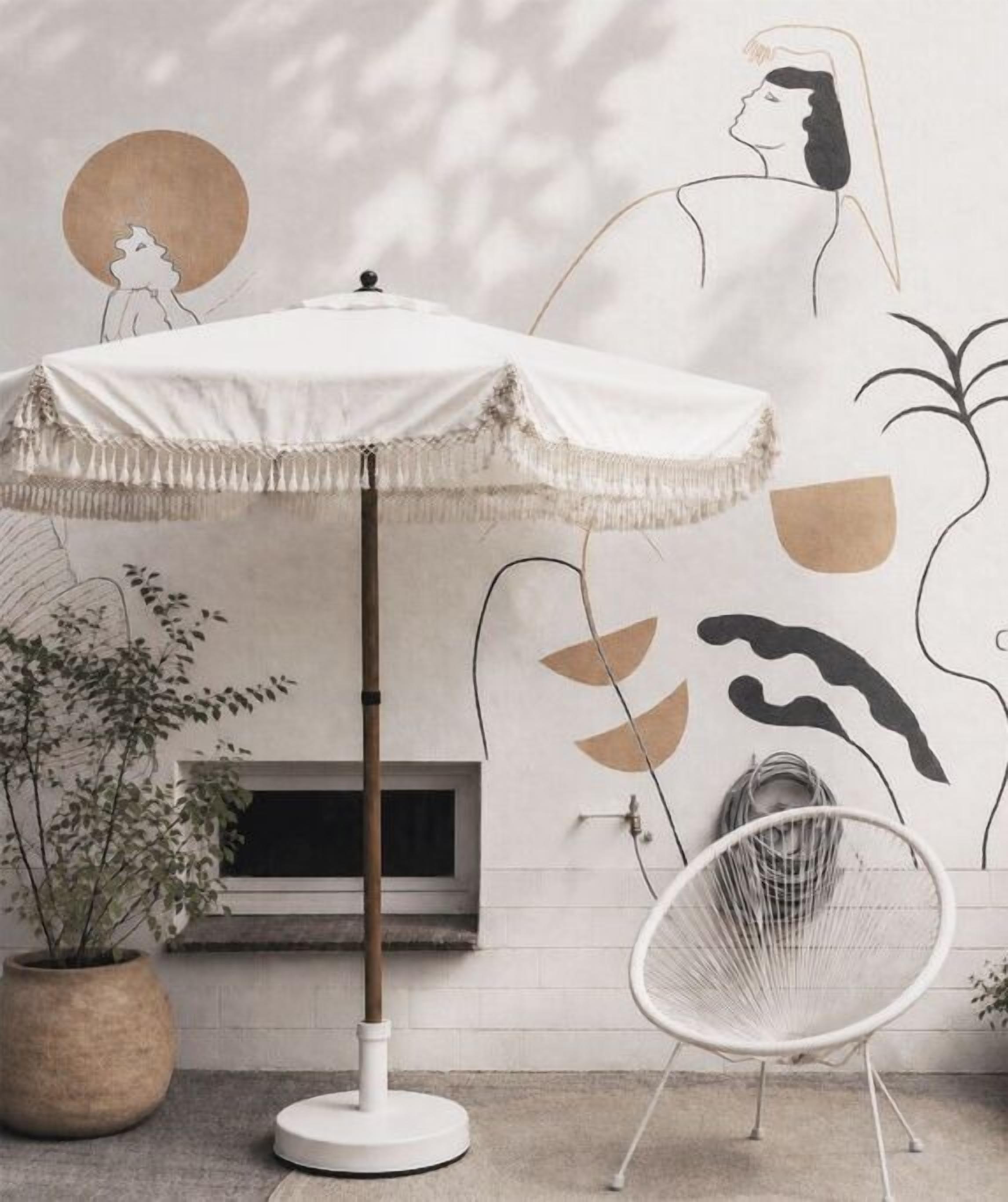 Una habitación con un paraguas blanco, una planta en maceta, una silla y una pared con arte abstracto.