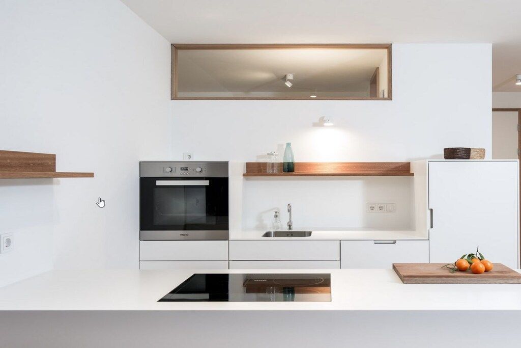 A modern kitchen with a built-in oven, a sink, and a wooden countertop.
