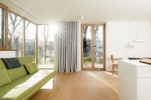 En moderne stue med en grøn sofa, spiseplads og et køkken.