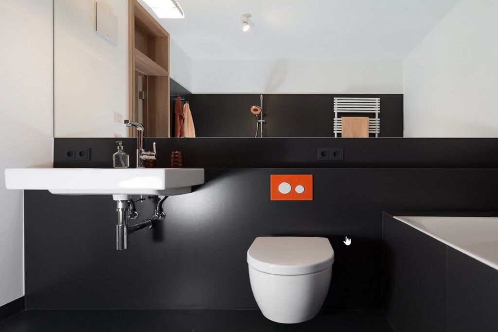 Et moderne badeværelse med en hvid vask, toilet og bruseniche.
