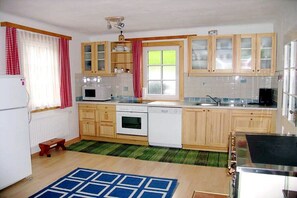 Een kleine keuken met houten kastjes, een magnetron, oven en vaatwasser.