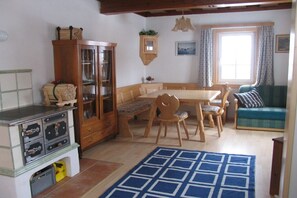 Un saló acollidor amb una taula de dinar de fusta, cadires, un armari i un sofà.
