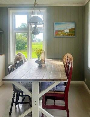 Comedor con una gran mesa de madera, sillas, una lámpara colgante y un cuadro en la pared.