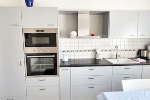 A kitchen with two ovens, a sink, and white cabinets. - Holiday apartment with 2 bedrooms (Utersum auf Föhr)