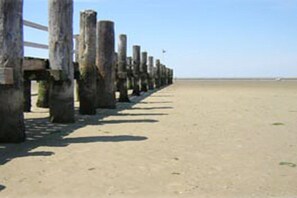 A concrete walkway with wooden posts, leading to a beach. - Holiday apartment with 2 bedrooms (Utersum auf Föhr)