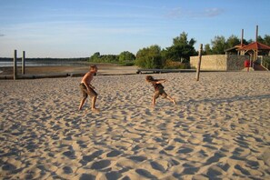 Ein Sandstrand mit einer Holzkonstruktion und einer Steinmauer im Hintergrund.