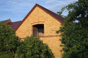 Ein Gebäude aus Backsteinen mit einem Satteldach und einem Fenster mit einem Metallgitter.