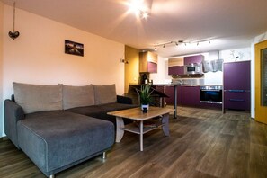 A modern living room with a grey sofa, a wooden coffee table, and a small potted plant. - Holiday apartment with 2 bedrooms (Hohnstein)