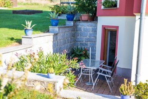 A patio area with a table and chairs, surrounded by potted plants and a stone wall. - Holiday apartment with 2 bedrooms (Hohnstein)