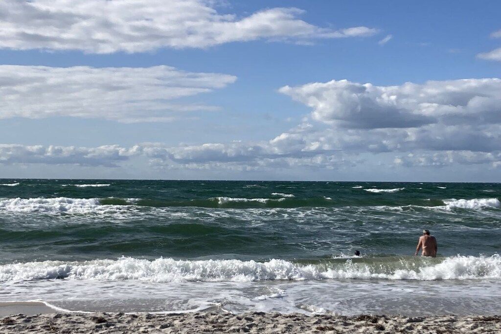 A beach with waves and a person in the water.