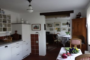 Eine traditionelle Küche mit weißen Schränken, einem Holzschrank und einem Essbereich mit Tisch für zwei Personen.
