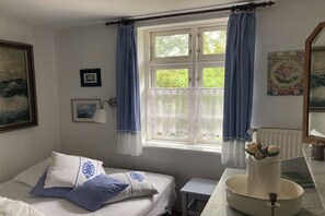 A bedroom with a bed, a small table, a window with curtains, and a radiator. - Holiday home in Born with swimming pool (Born)