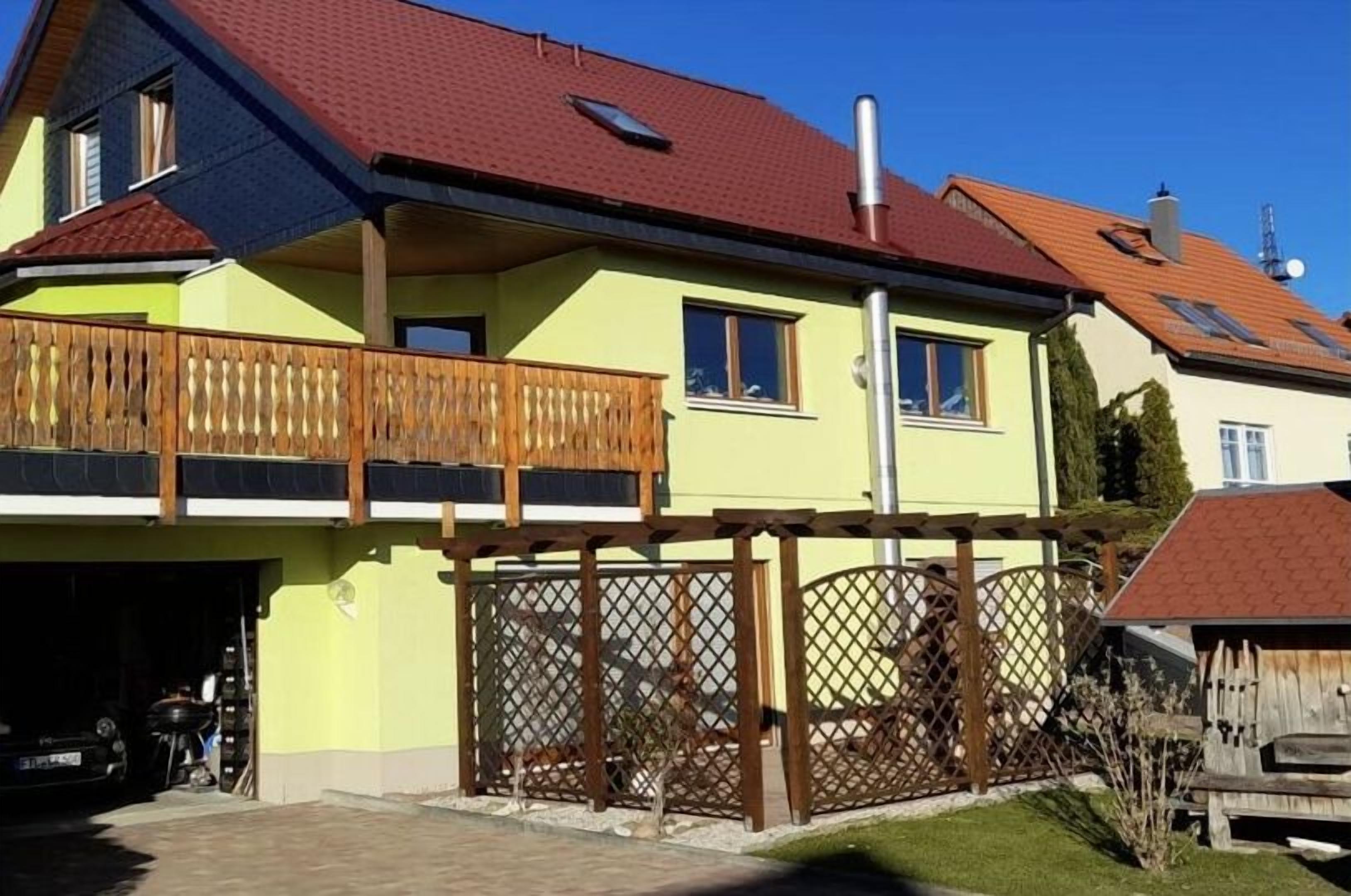 Ein zweigeschossiges Haus mit Balkon, Garage und umzäunter Garten.
